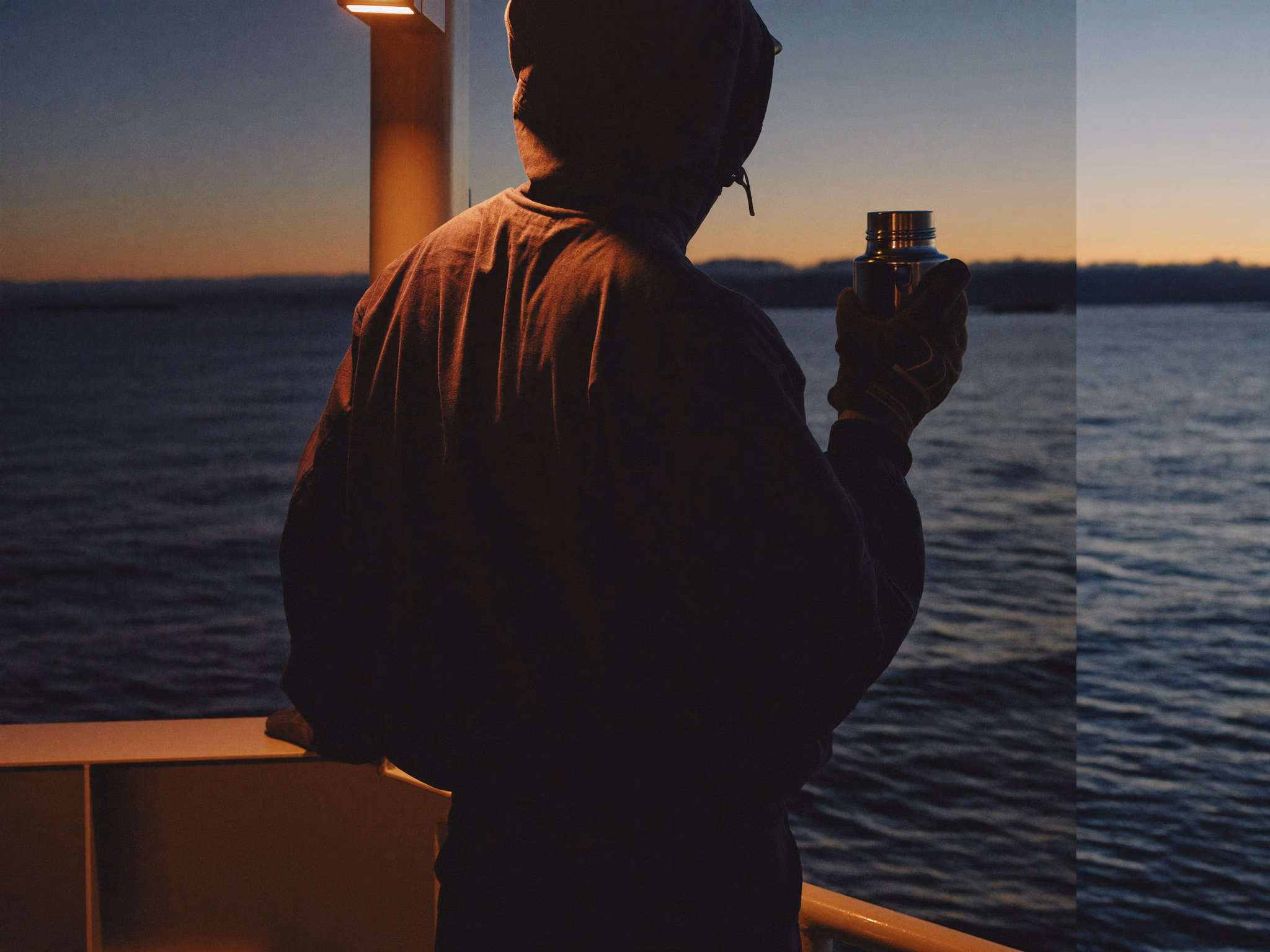 Worker having a quiet moment with a thermos on a ship deck at sunset