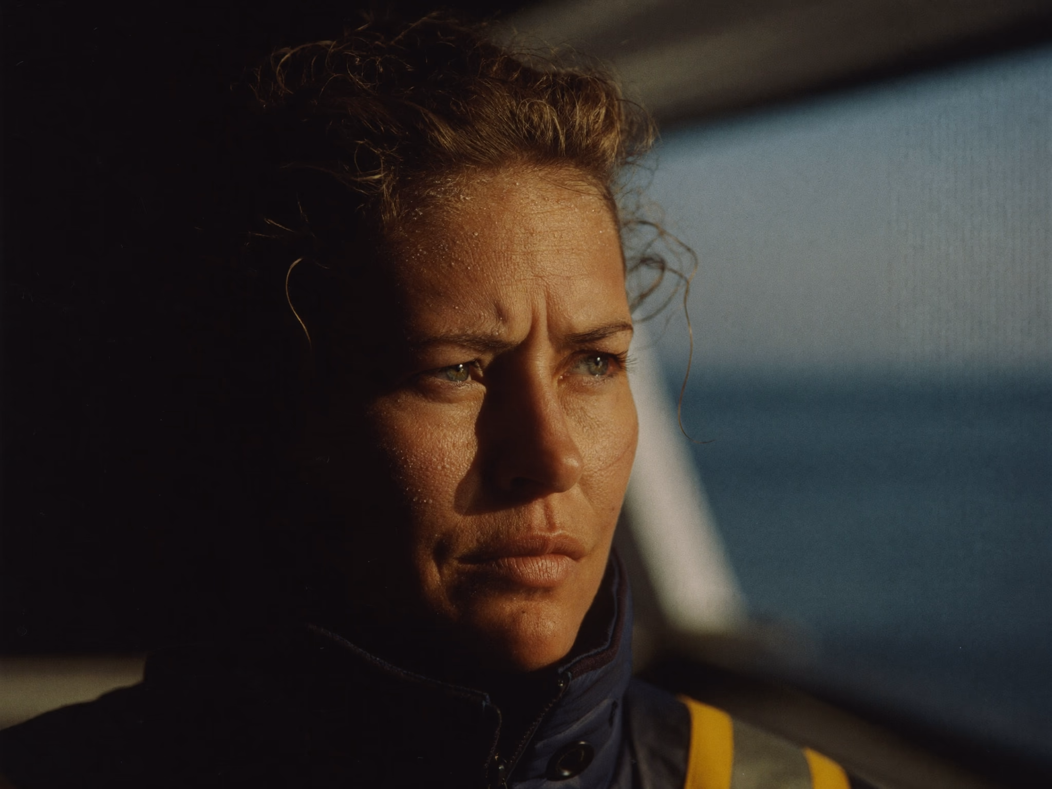 Woman in industrial workwear at a ship cabin window
